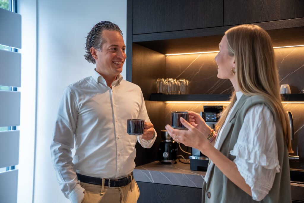 Makelaar van Kocken Makelaars in een ontspannen gesprek met een klant bij de koffie op kantoor