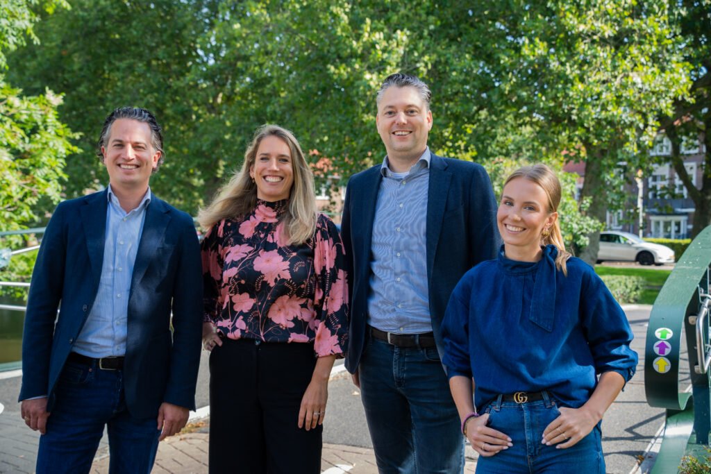 Het team van Kocken Makelaars in Purmerend staat lachend buiten in een groene straat