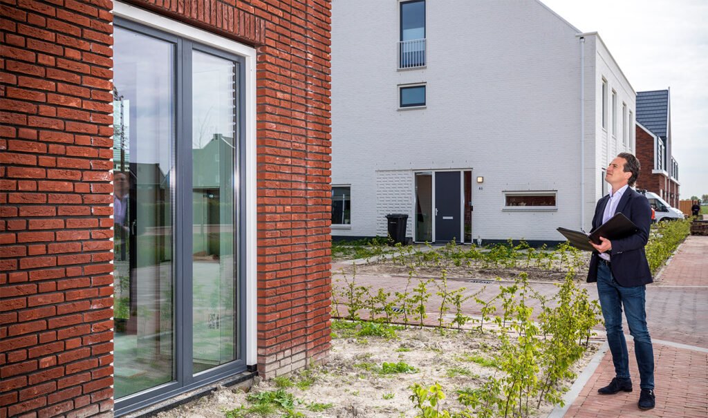 Makelaar van Kocken Makelaars met map bekijkt de gevel van een nieuwbouwwoning in Purmerend voor een gratis waardebepaling
